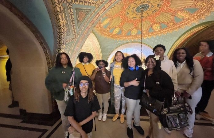  A group of nine students pose together inside an ornate building with colorful, patterned arches an